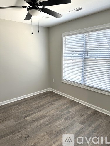 A room with a ceiling fan and a window with blinds.