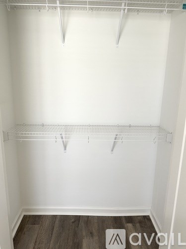 Empty white closet with wooden floor and white shelves.