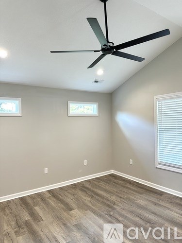 A room with a ceiling fan and two windows.