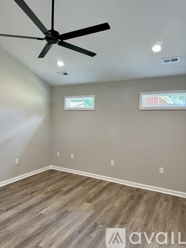 A room with a ceiling fan and two windows.