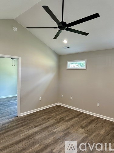 A room with a ceiling fan and wooden flooring.