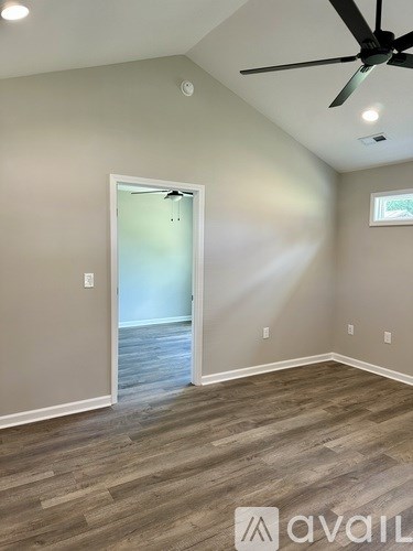 A room with a ceiling fan and a door leading to another room.