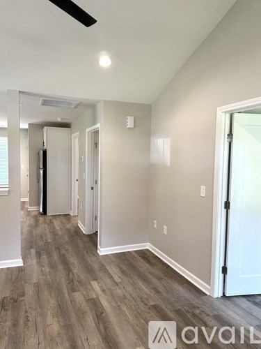 A hallway with wood flooring and white walls.