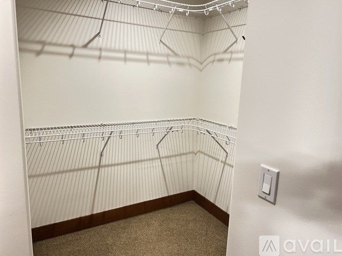 A white wall with a light switch and a carpeted floor.
