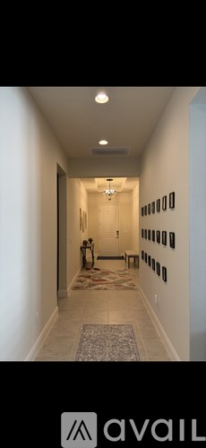 A hallway with a rug and a chandelier.