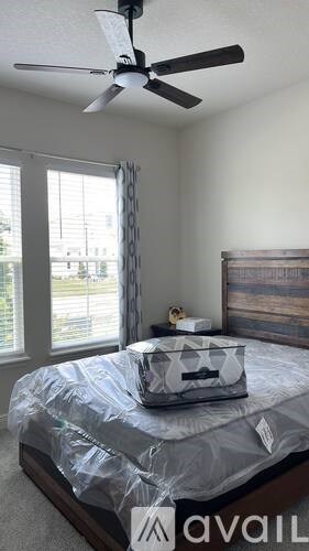 A bedroom with a bed covered in a plastic sheet and a ceiling fan.