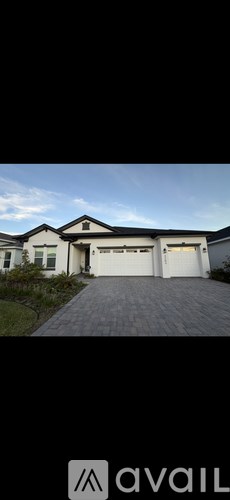 A white house with a black roof and a garage door.