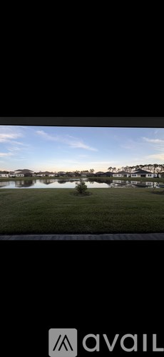 A grassy field with a tree and buildings in the distance.