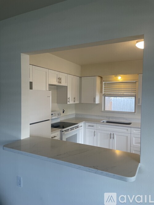 A kitchen with white cabinets and appliances.