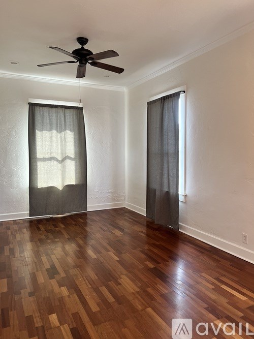 A room with a ceiling fan and wood flooring.