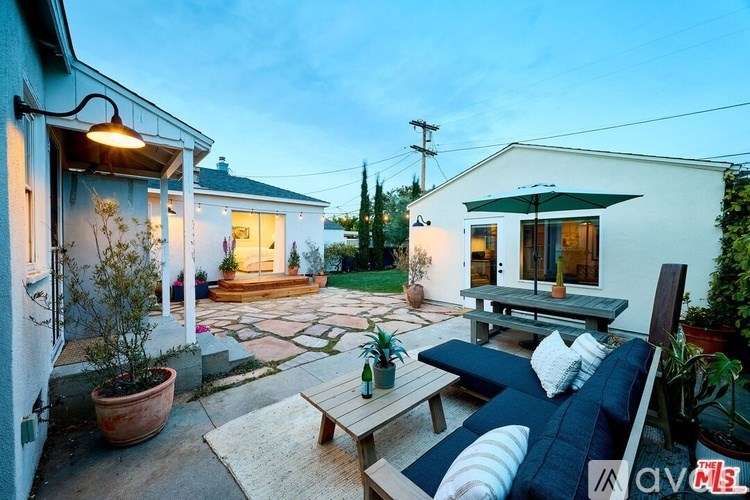 A patio with a couch, table, and potted plants.