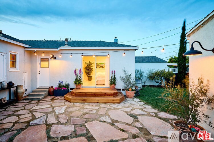 A house with a stone patio and a lit up entrance.