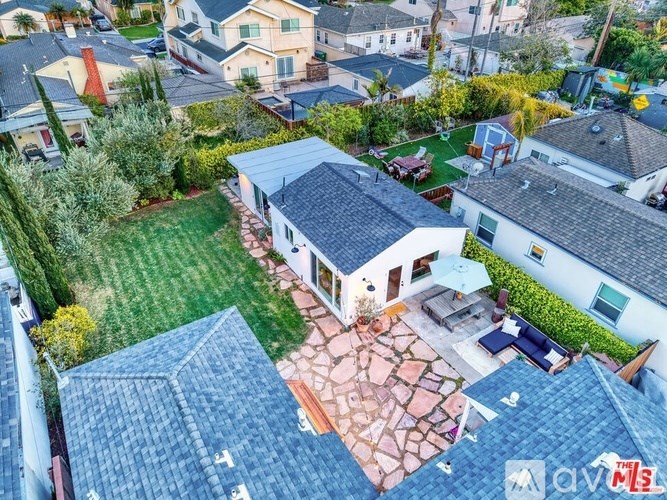 A house with a red brick patio is surrounded by other houses.
