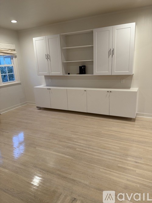 A kitchen with white cabinets and a wooden floor.