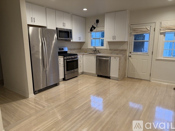 A kitchen with white cabinets and a stainless steel refrigerator.