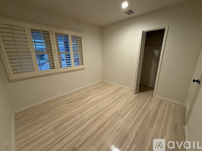 A room with wooden flooring and a doorway leading to another room.
