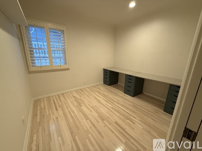 A room with wooden flooring and a window with blinds.