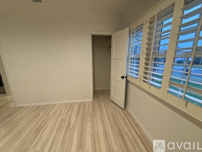 A room with wooden flooring and a white door with a window on the side.