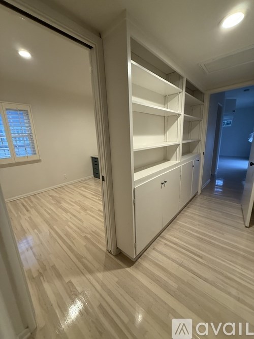 A room with a white shelving unit and wooden flooring.