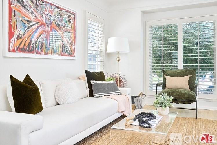 A white couch with pillows and a painting on the wall.