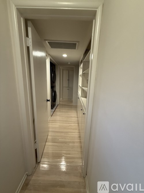 A long hallway with a door on the left and a washer and dryer in the background.