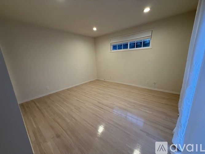 A room with wooden flooring and a window with blinds.