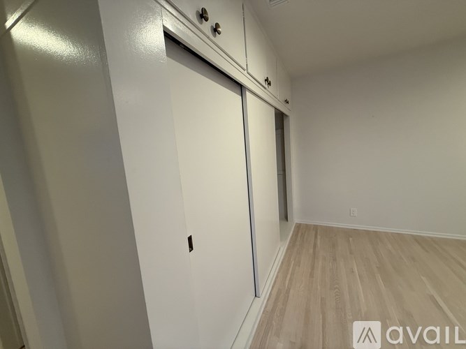 A room with a white door and a wooden floor.