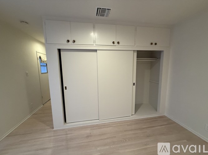 A room with a white door and a small window on the left wall.