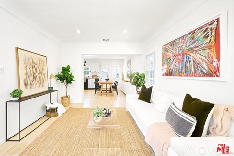 A living room with a white couch and a large painting on the wall.