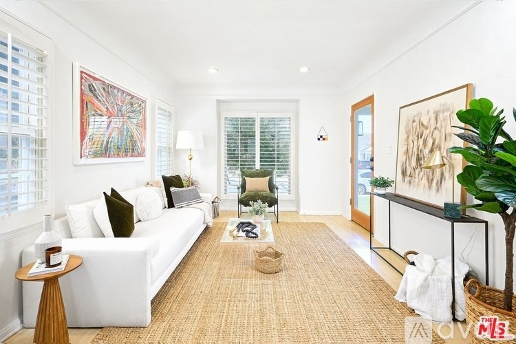 A living room with a white couch, a rug, and a painting on the wall.