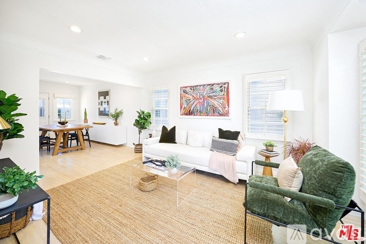 A living room with a white couch, a green armchair, and a painting on the wall.
