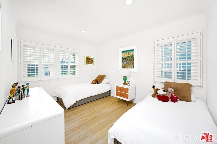 A white bedroom with two beds and a nightstand.