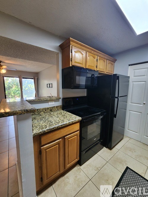 A kitchen with black appliances and wooden cabinets.
