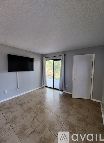 A room with a television and sliding glass doors.
