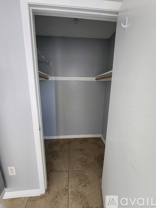A small white closet with a shelf and a light switch on the wall.