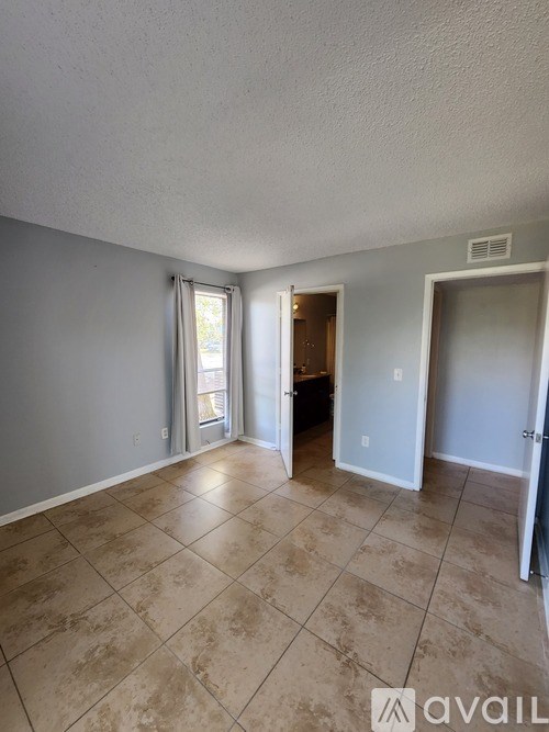 A room with tile flooring and a doorway leading to another room.