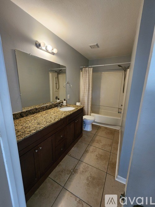 A bathroom with a granite countertop and a toilet.