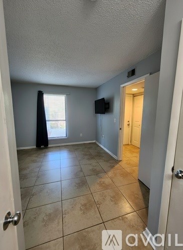 A living room with a flat screen TV and a window with blinds.