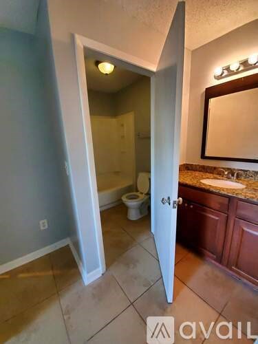 A bathroom with a toilet, sink, and mirror.