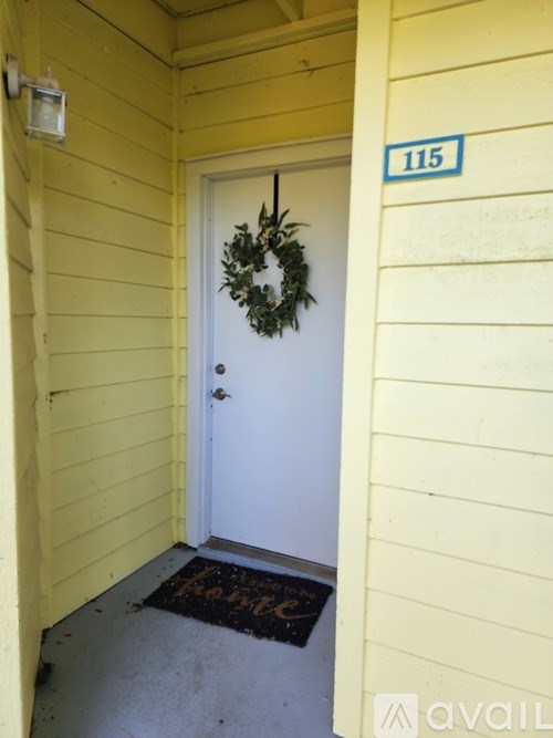A door with a wreath on it and a sign above it that says 115.
