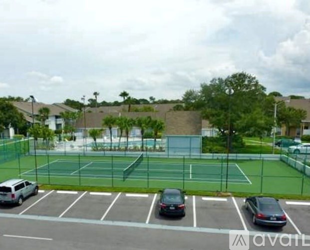 A tennis court surrounded by a parking lot.