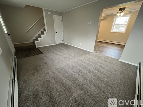 A room with a carpeted floor and a staircase leading to another room.