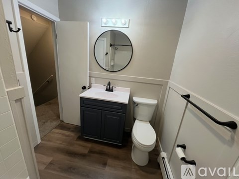 A bathroom with a toilet, sink, and mirror.