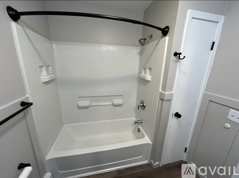 A white bathroom with a white tub and a white door.