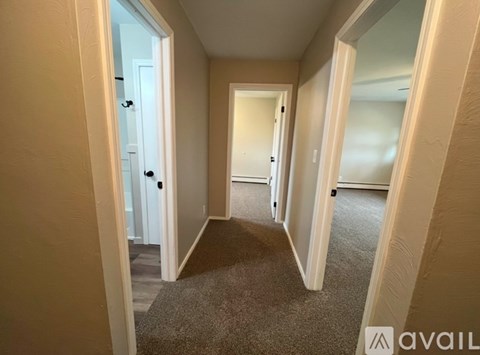 A hallway with a carpeted floor and white walls.