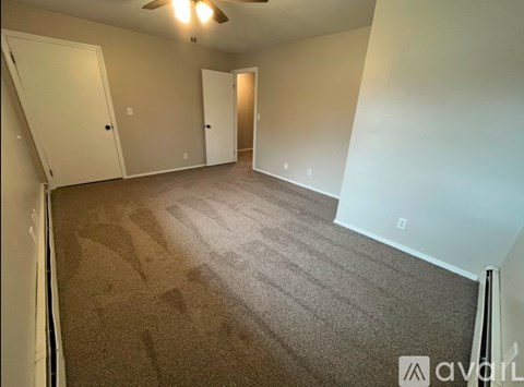 A room with carpeted floor and a ceiling fan.