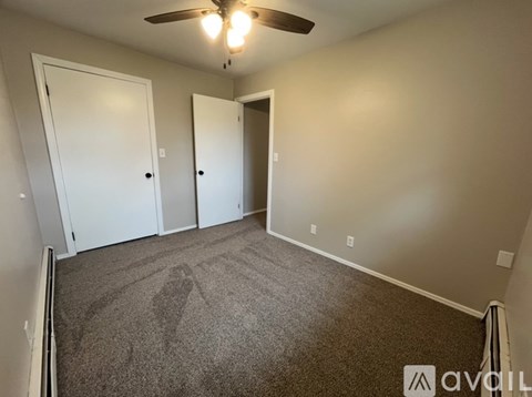 A room with a carpeted floor and a ceiling fan.