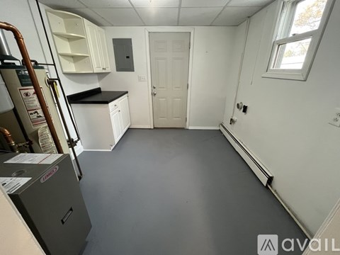 A kitchen with white cabinets and a grey floor.