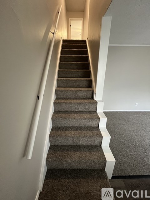 A staircase with a carpeted runner and white handrails.
