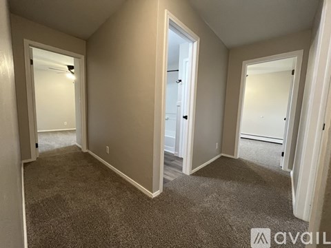 A room with carpeted floor and white walls, with a doorway leading to another room.